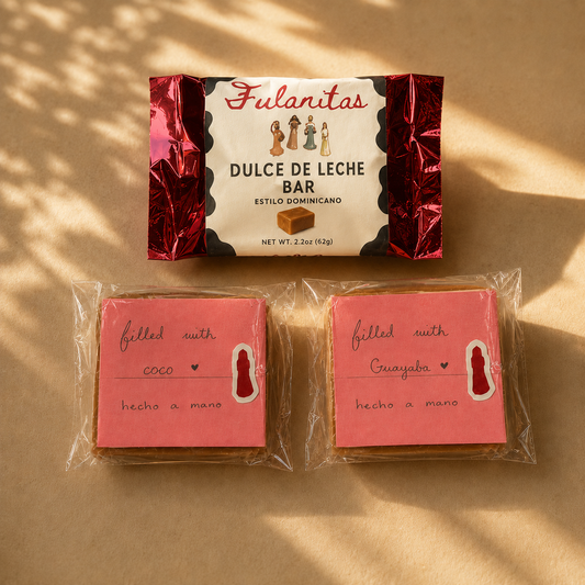 A package of Fulanitas Dulce de Leche Bar alongside two individually wrapped pink dulce de leche bar, one filled with coconut and the other filled with guayaba (guava in dominican spanish) on a warm beige background with soft leaf shadows.